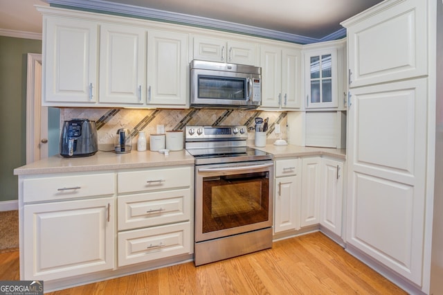 kitchen featuring ornamental molding, white cabinetry, light hardwood / wood-style floors, and appliances with stainless steel finishes