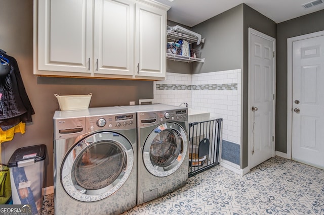 laundry room featuring cabinets, tile walls, and washing machine and clothes dryer