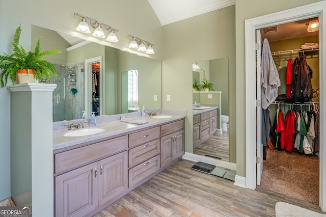 bathroom with vanity, a shower with shower door, hardwood / wood-style flooring, crown molding, and toilet