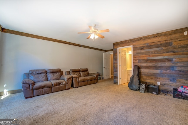 carpeted living room with wood walls, ceiling fan, and crown molding