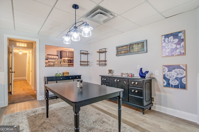 office area with light hardwood / wood-style flooring, an inviting chandelier, and a paneled ceiling