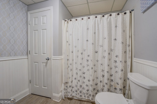 bathroom featuring a shower with shower curtain, wood-type flooring, a paneled ceiling, and toilet