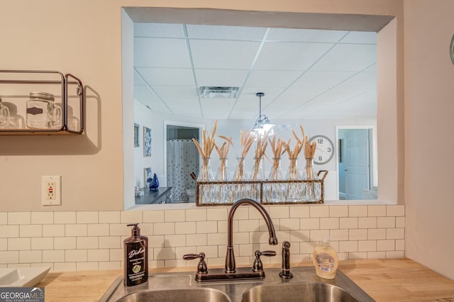 kitchen featuring butcher block countertops, a drop ceiling, a chandelier, and sink