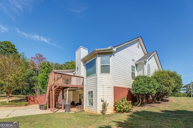 rear view of house featuring a wooden deck, a yard, and a patio area