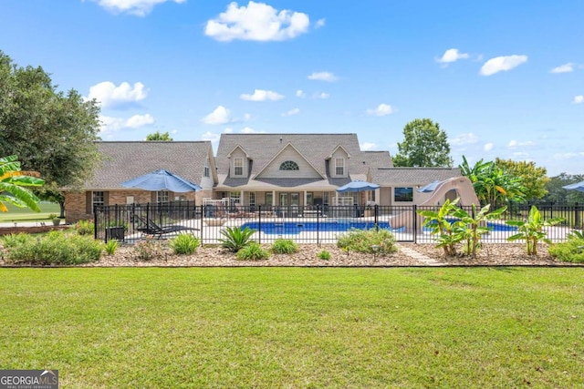 back of property featuring a fenced in pool and a lawn