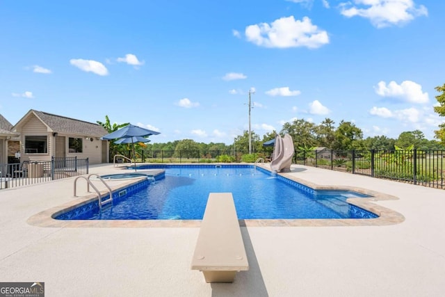 view of swimming pool with a diving board, a water slide, and a patio area