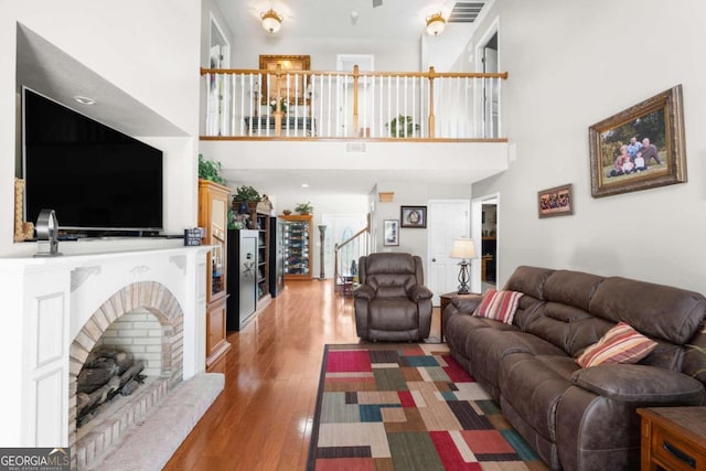 living room featuring a fireplace, a towering ceiling, and hardwood / wood-style floors