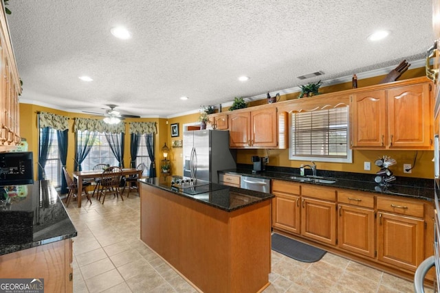 kitchen featuring ornamental molding, ceiling fan, a center island, and a textured ceiling