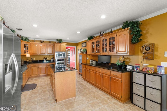 kitchen with ornamental molding, a textured ceiling, appliances with stainless steel finishes, and a kitchen island