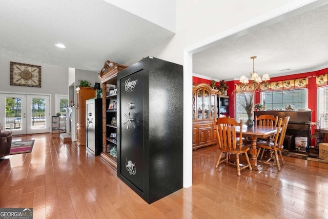 dining area featuring french doors, an inviting chandelier, hardwood / wood-style floors, and a textured ceiling