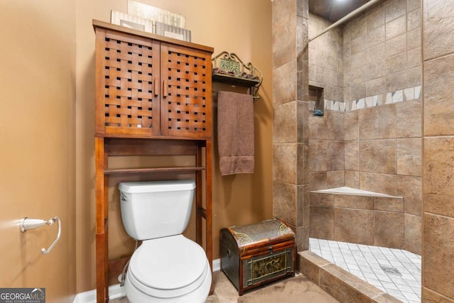 bathroom with a tile shower and toilet