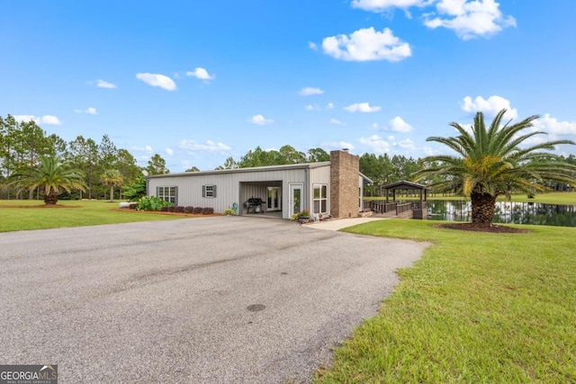 375 Dasher St, Lyons, GA 30436 - view of front facade with a front yard, a detached garage, a water view, and an outbuilding