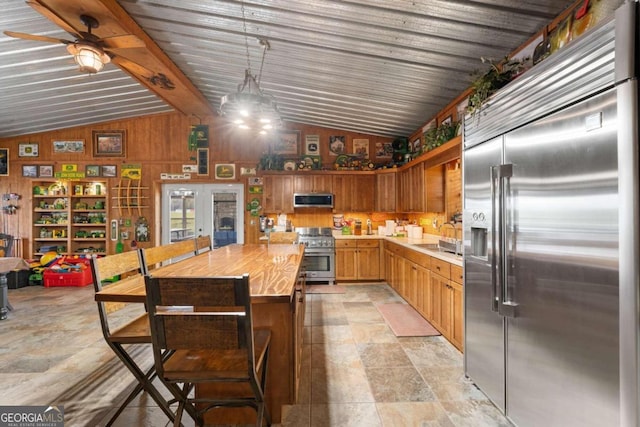 kitchen featuring wood walls, butcher block counters, vaulted ceiling with beams, ceiling fan, and high quality appliances