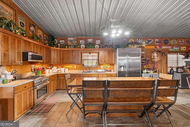 kitchen with premium appliances, lofted ceiling, hanging light fixtures, and sink