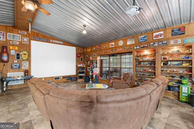 living room featuring ceiling fan, wood walls, and vaulted ceiling