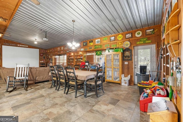 dining space with lofted ceiling and wood walls