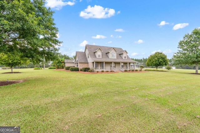 back of property featuring covered porch and a yard