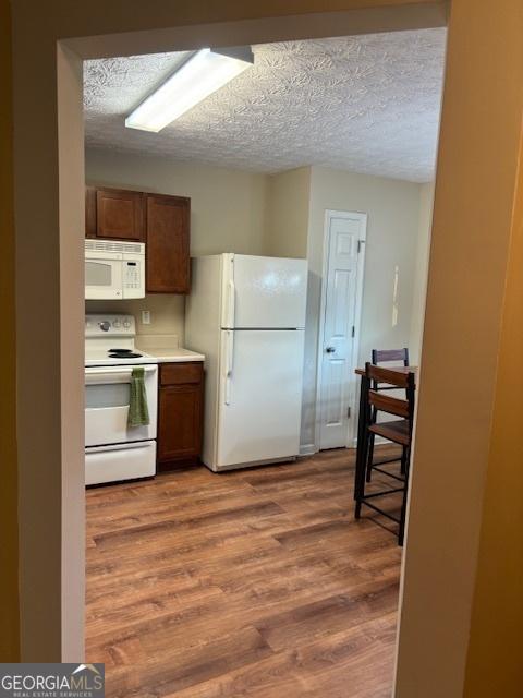 kitchen featuring white appliances, hardwood / wood-style floors, and a textured ceiling