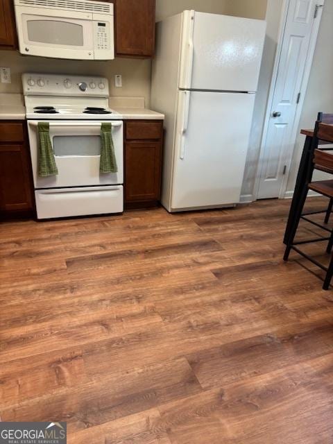 kitchen with white appliances and light hardwood / wood-style floors