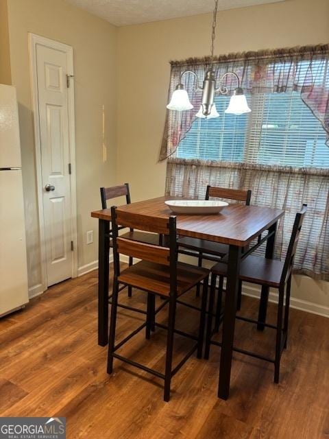 dining room with an inviting chandelier, a textured ceiling, and dark hardwood / wood-style flooring