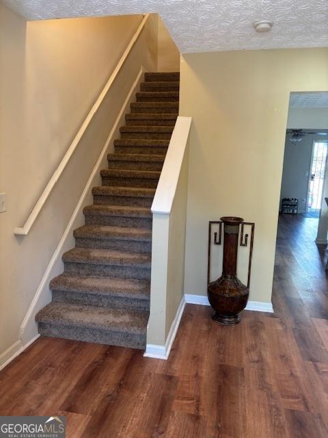 staircase featuring wood-type flooring and a textured ceiling