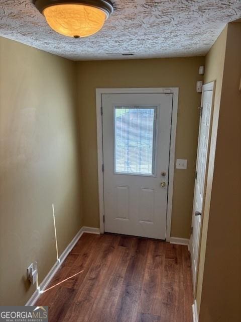 doorway with a textured ceiling and dark wood-type flooring