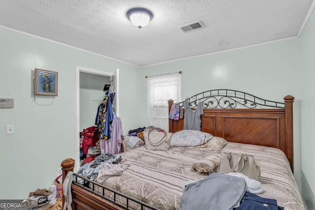 bedroom featuring a closet, ornamental molding, a textured ceiling, and a walk in closet