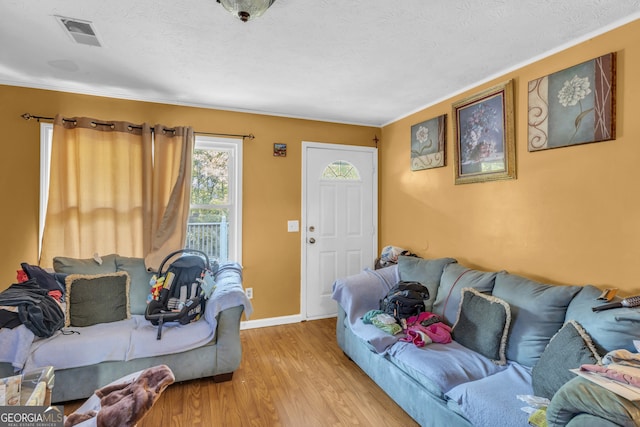 living room with light hardwood / wood-style flooring, a textured ceiling, and crown molding