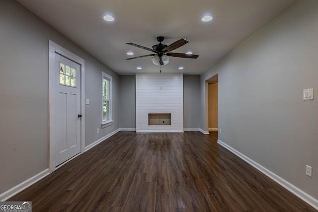 unfurnished living room with ceiling fan, dark hardwood / wood-style floors, and a large fireplace