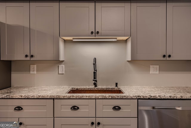 kitchen featuring light stone counters, sink, and stainless steel dishwasher