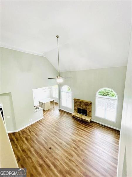 unfurnished living room with a stone fireplace, a ceiling fan, lofted ceiling, and wood finished floors