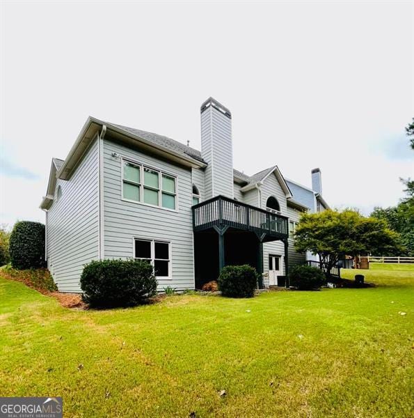 rear view of property with a wooden deck and a lawn