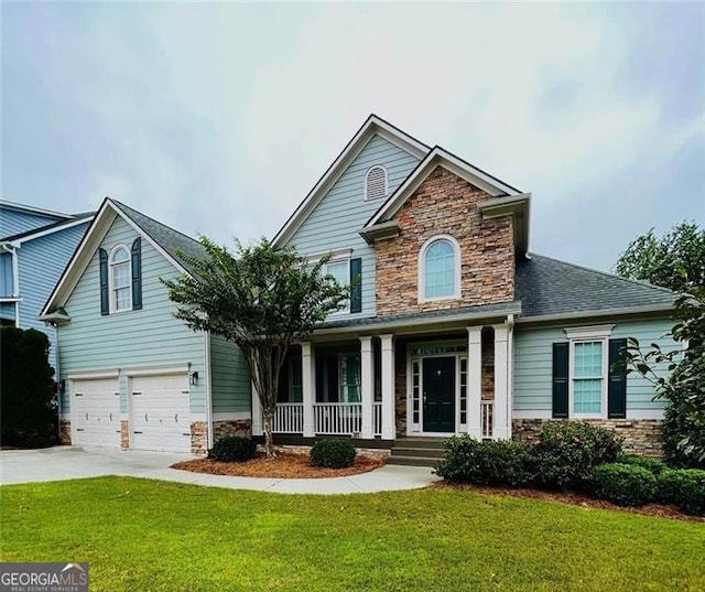 view of front of house with a front yard, concrete driveway, covered porch, and stone siding