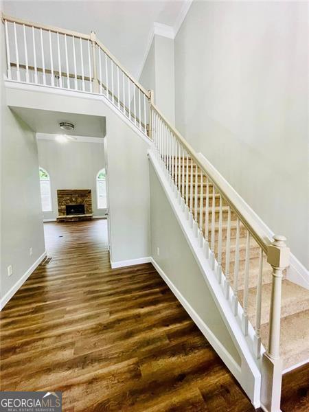 stairway featuring baseboards, wood finished floors, a towering ceiling, and ornamental molding