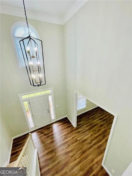 entryway featuring crown molding, a notable chandelier, wood finished floors, and a wealth of natural light