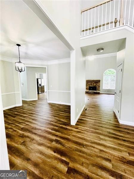 foyer entrance featuring baseboards, a stone fireplace, wood finished floors, and crown molding