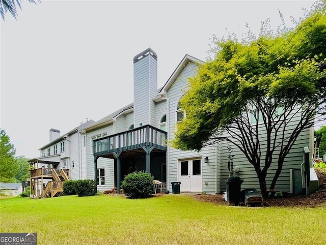 back of property with a yard, a deck, and a chimney