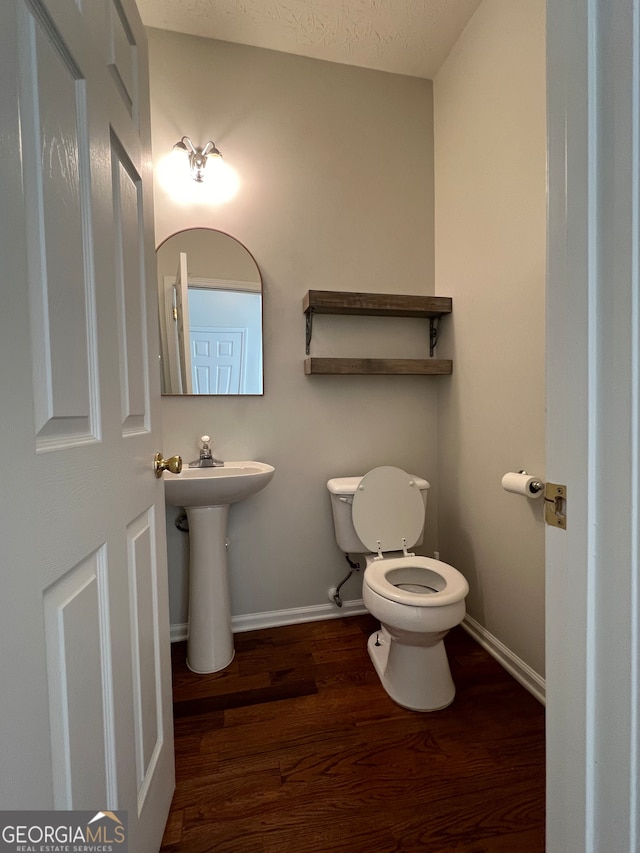 bathroom with hardwood / wood-style flooring, sink, toilet, and a textured ceiling