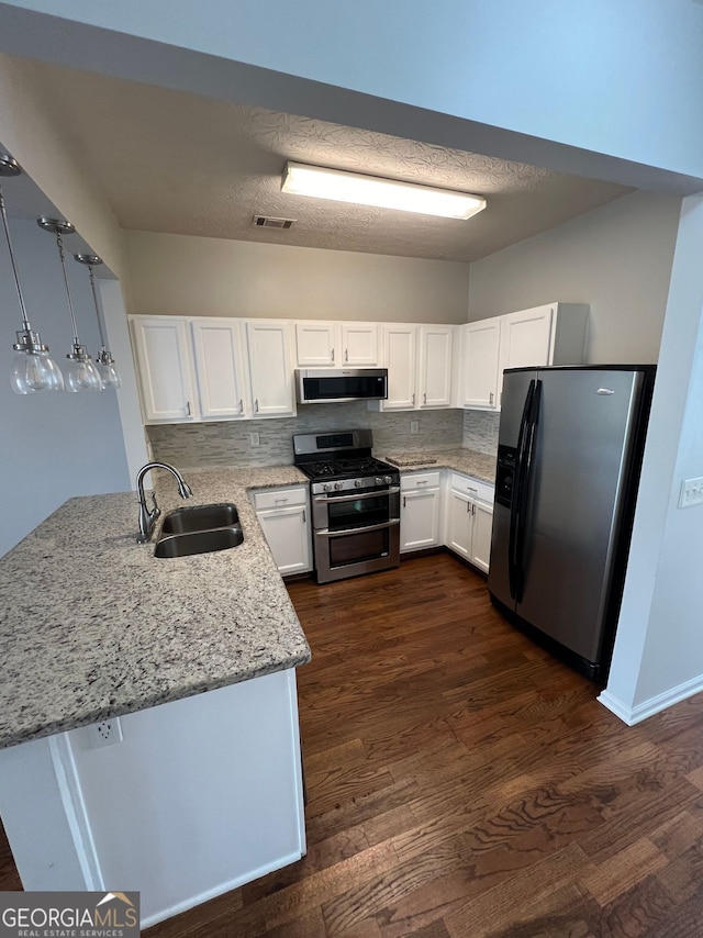 kitchen featuring stainless steel appliances, dark wood-type flooring, sink, white cabinets, and hanging light fixtures