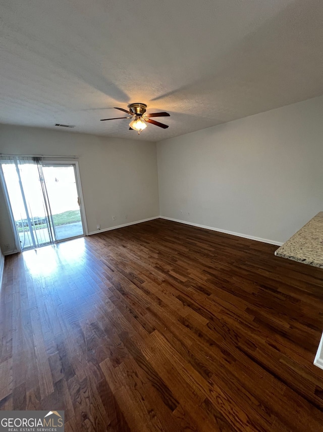 spare room with a textured ceiling, ceiling fan, and dark wood-type flooring