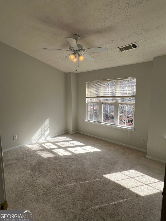 carpeted empty room with ceiling fan and a textured ceiling