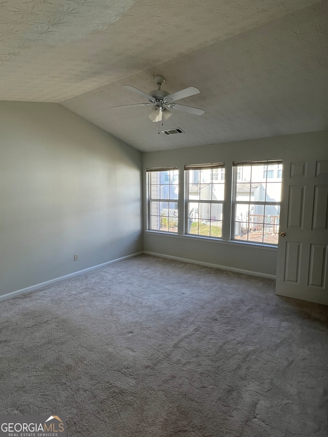 carpeted empty room with a textured ceiling, ceiling fan, and vaulted ceiling