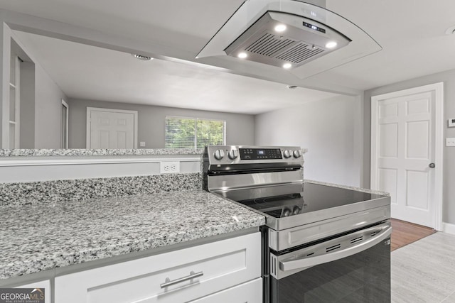 kitchen featuring light wood-style floors, white cabinets, stainless steel electric range oven, and light stone countertops