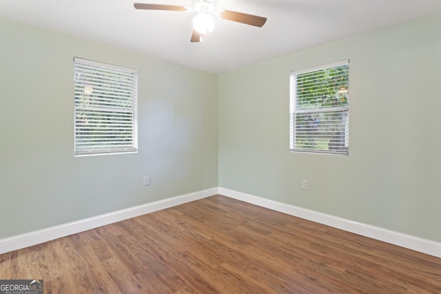 empty room with baseboards, ceiling fan, wood finished floors, and a healthy amount of sunlight