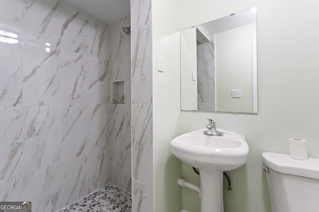 bathroom featuring toilet and a marble finish shower