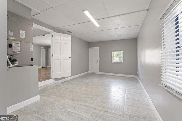 spare room featuring a paneled ceiling and light wood-type flooring