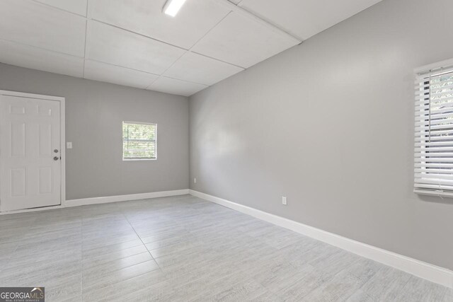 empty room with light hardwood / wood-style flooring and a drop ceiling