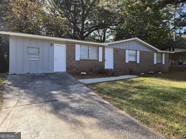 ranch-style house featuring brick siding, board and batten siding, and a front yard