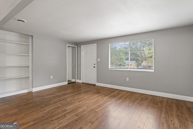 unfurnished living room featuring visible vents, wood finished floors, built in features, and baseboards