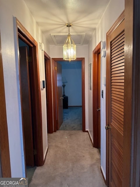 corridor with carpet floors and a chandelier